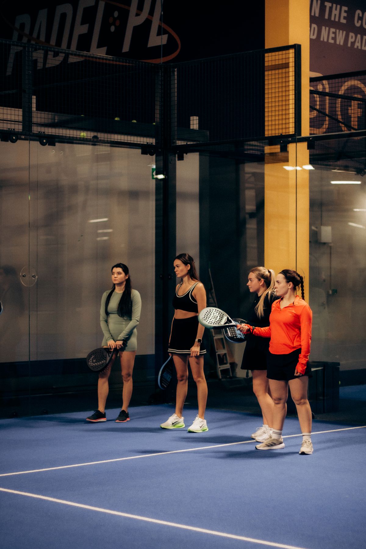 Four padel players lined up on an indoor court
